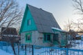 Empty suburban plot covered with snow and left for the winter brick cottage house on wintery evening at sunset. Russian dacha