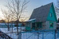 Empty suburban plot covered with snow and left for the winter brick cottage house on wintery evening at sunset. Russian dacha