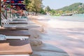 Empty sun lounge chairs under umbrellas standing close to seashore line during high tide water. Perspective view. Tropical