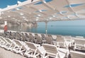 Empty sun loungers under a canopy on the beach. The beach area is empty. No people. White plastic sunbeds under the sun Royalty Free Stock Photo