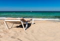 Empty sunbed in front of turquoise water