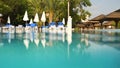 Empty sunbeds and closed parasols on morning, by the hotel pool. Photographed from water level. Vacation background, space for Royalty Free Stock Photo