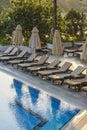 Empty sunbeds and closed parasols on morning, by the hotel pool. Swimming pool in luxury hotel resort near sea. Beautiful morning Royalty Free Stock Photo