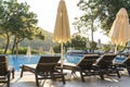 Empty sunbeds and closed parasols on morning, by the hotel pool. Swimming pool in luxury hotel resort near sea. Beautiful morning Royalty Free Stock Photo