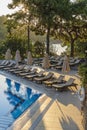 Empty sunbeds and closed parasols on morning, by the hotel pool. Swimming pool in luxury hotel resort near sea. Beautiful morning Royalty Free Stock Photo