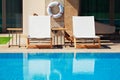 empty sunbeds near hotel and swimming pool and life buoy hanging on the wall