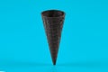 Empty, sweet black wafer cone for ice cream on blue background. Concept of food, treats. Mockup, template for your