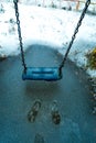 Empty swing in the playground in the park, wooden swing, wooden swing in winter, icicles on the swing Royalty Free Stock Photo