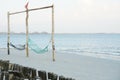 Empty swing weaved by rope hanging on the wooden poles on the beach with seascape background Royalty Free Stock Photo