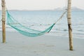 Empty swing weaved by rope hanging on the wooden poles on the beach with seascape background Royalty Free Stock Photo