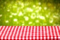 Empty table background. Empty wooden deck table covered with a red checkered tablecloth in front of abstract blurred fresh Royalty Free Stock Photo