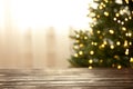 Empty table and blurred fir tree with yellow Christmas lights on background, bokeh effect Royalty Free Stock Photo