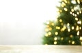 Empty table and blurred fir tree with yellow Christmas lights on background, bokeh effect Royalty Free Stock Photo