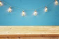 empty table in front of Christmas tree in the masson jar garland lights over wooden blue background.