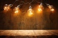 empty table in front of Christmas warm gold garland lights on wooden background.