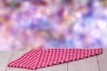 Empty table product. Closeup of a empty red checkered tablecloth or napkin on a rustic bright table over abstract colorful pastel