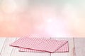 Empty table product. Closeup of a empty red checkered tablecloth or napkin on a rustic bright table over abstract pastel pink