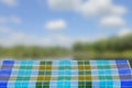 Empty table product. Empty wooden deck table covered with a blue checkered tablecloth over abstract blurred natural backdrop. Royalty Free Stock Photo