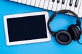 Empty Tablet with headphone and keyboard on blue background Royalty Free Stock Photo