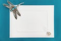 An empty template with white paper frame on blue background, decorated with jewelry. Silver dragonfly brooch at the corner of the