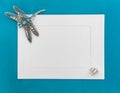 An empty template with white paper frame on blue background, decorated with jewelry. Silver dragonfly brooch at the corner of the