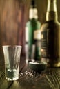 An empty tequila glass in front of many colorful liquor bottles, shallow depth of field, selective focus.