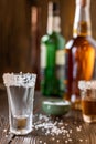 An empty tequila glass, with salt at the edges, stands on the bar, in the background are different bottles of alcohol