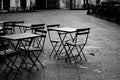 Empty terrace with tables and chairs in wood and metal at coffee and resteurant beside sidewalk in center city. Environment city