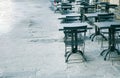 Empty terrace with tables and chairs in wood and metal at coffee and resteurant beside sidewalk in center city. Environment city