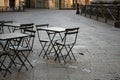 Empty terrace with tables and chairs in wood and metal at coffee and resteurant beside sidewalk in center city. Environment city