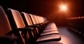 Empty theater seats illuminated by warm spotlight in a dark auditorium with shallow depth of field and dramatic lighting Royalty Free Stock Photo