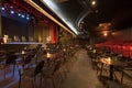 An empty theater with stalls with tables and a stage with four folding chairs and red fabric seats