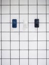 Empty three modern towel hooks, blue and white hanging on white grid wall bathroom. Royalty Free Stock Photo