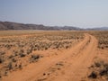 Empty tire track dirt road in Namib desert with mountains, Damaraland, Namibia, Southern Africa Royalty Free Stock Photo