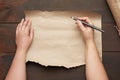 Empty torn sheet of brown craft paper and two hands with a black wooden pencil Royalty Free Stock Photo