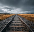 Empty train tracks stretching into a cloudy sky over a field Royalty Free Stock Photo