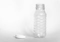 Empty transparent open plastic bottle without cap, cap lies next to a white background, the concept of debris removal