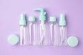 Empty travel cosmetic bottles on violet background. Minimalist bodycare beauty products for vacation or journey. Top view. Royalty Free Stock Photo