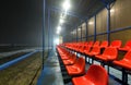 Empty tribune with rows wet red plastic seats on a football field Royalty Free Stock Photo