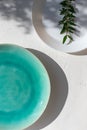 Empty turquoise ceramic plate on white plaster background with myrtle leaves shadows. Royalty Free Stock Photo