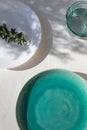 Empty turquoise ceramic plate on white plaster background with myrtle leaves shadows. Spring or summer table setting. Royalty Free Stock Photo