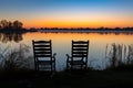 empty twin chairs facing calm lake during sunrise Royalty Free Stock Photo