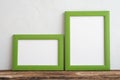 Empty two green photo frame on old wooden table over white wall background copy space. Home decoration, creative idea design Royalty Free Stock Photo