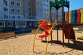 Empty urban residential infrastructure, nobody - children`s playground next to a condominium. Swing, slide, stairs, multistory