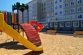 Empty urban residential infrastructure, nobody - children`s playground next to a condominium. Swing, slide, stairs, multistory