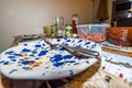 Empty used colorful plate with fork spoon and knife after food eaten on wooden dinner table Royalty Free Stock Photo