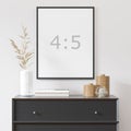 Empty vertical frame 4:5 on white wall with black dresser, white vase and wood decor. Royalty Free Stock Photo