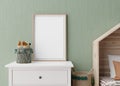 Empty vertical picture frame on green wall in modern child room. Mock up interior in scandinavian style. Free, copy