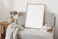 Empty vertical picture frame mockup. Midcentury linen sofa with linen blanket. Ceramic vase with dry hydrangea flowers Royalty Free Stock Photo