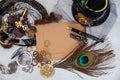 An empty vintage postcard for a close-up message, surrounded by women`s jewelry, lace with fur and steampunk gears mechanisms and